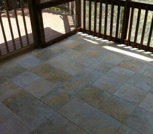 A patio with tile flooring and wooden railing.