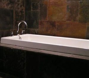 A bathroom with a large white tub and tiled walls.